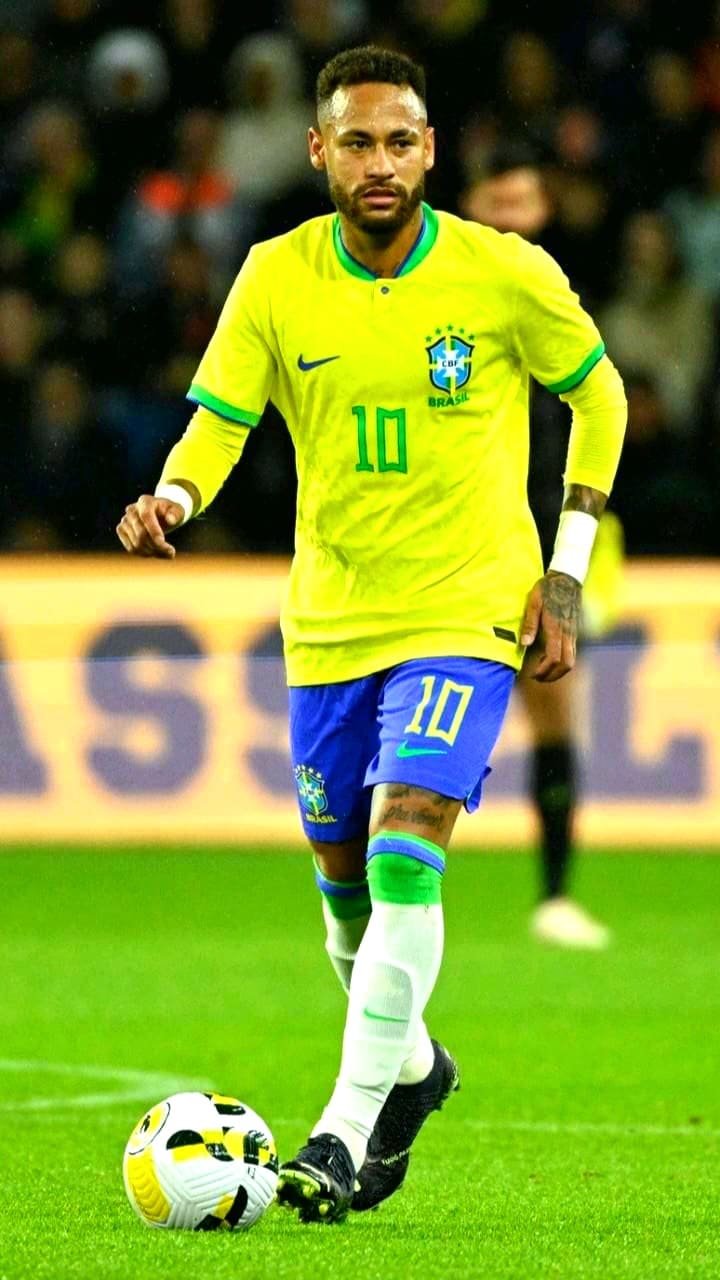 A male soccer player in a yellow Brazil jersey with number 10 dribbles a ball on the field during a match. Watch all his moves live with Bulgaria IPTV; he has short hair, blue shorts, white socks, and soccer cleats.
